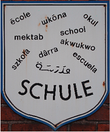 Ein Schild mit dem Schriftzug Schule in verschiedenen Sprachen
