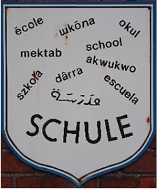 Ein Schild mit dem Schriftzug Schule in verschiedenen Sprachen
